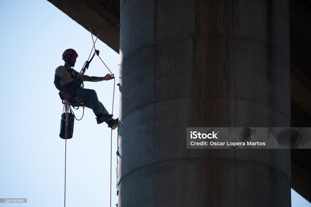industrial climber inspecting a bridge pylon using rope access techniques